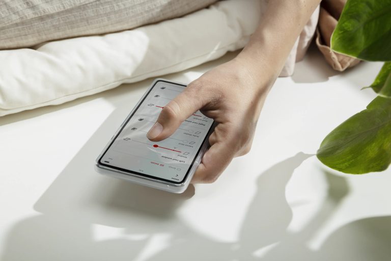 Donna con smartphone davanti alle finestre per tetti con tende