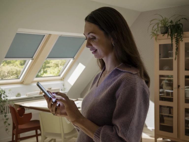 Donna che comanda tende elettriche con lo smartphone in mansarda