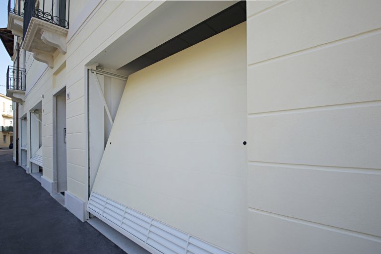 Primo piano dell'anta basculante sollevata con bracci e griglia, facciata crema