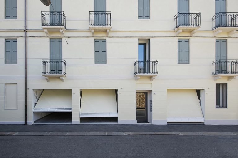Palazzo storico ristrutturato color crema con tre basculanti aperte al piano terra