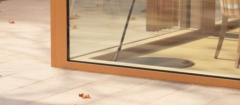 Dettaglio del telaio in legno di una portafinestra a tutto vetro sul pavimento