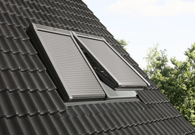 Due finestre per tetti con tapparelle solari chiuse su tetto scuro